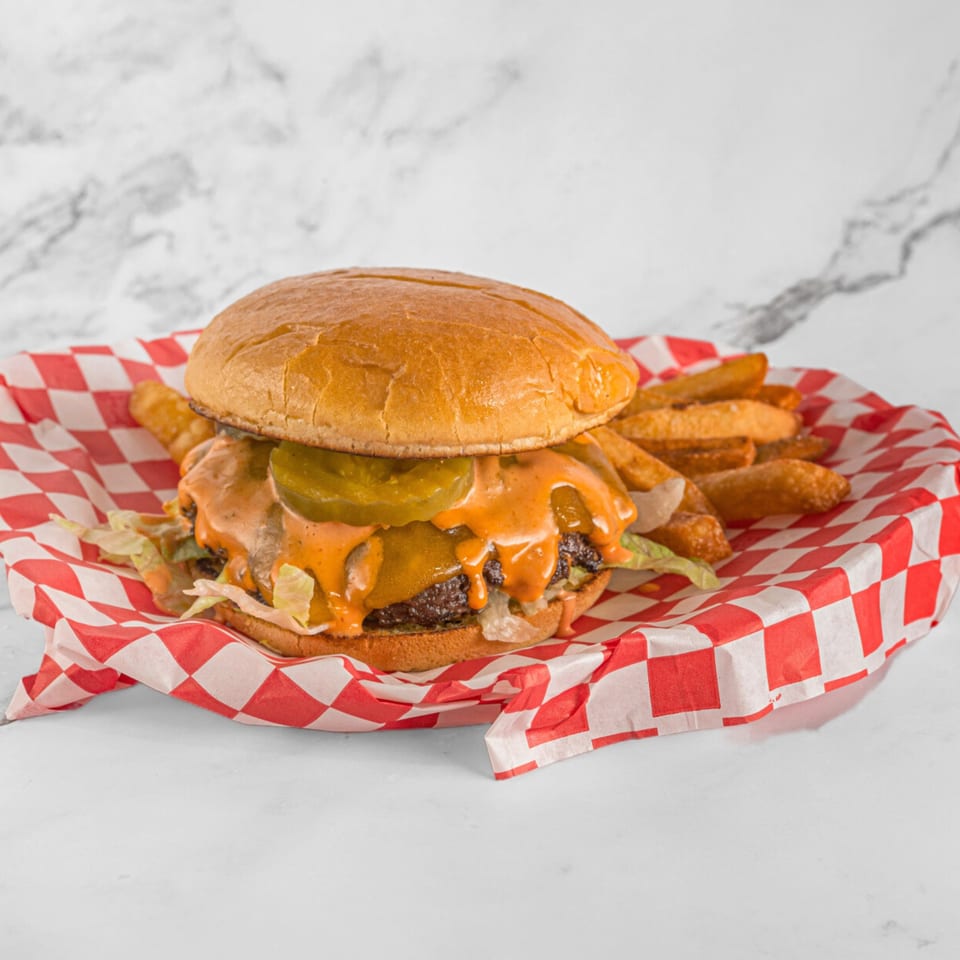 A Hot Chicken and Breakfast fast-food burger with pickles, sauce, and fries in a red checkered basket.