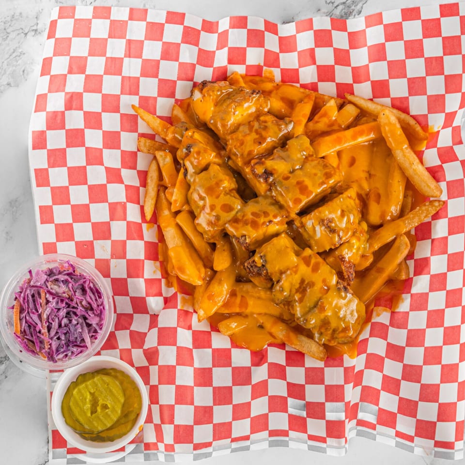 Hot Chicken and Breakfast's cheesy fries with chicken, coleslaw, and pickles on checkered paper.