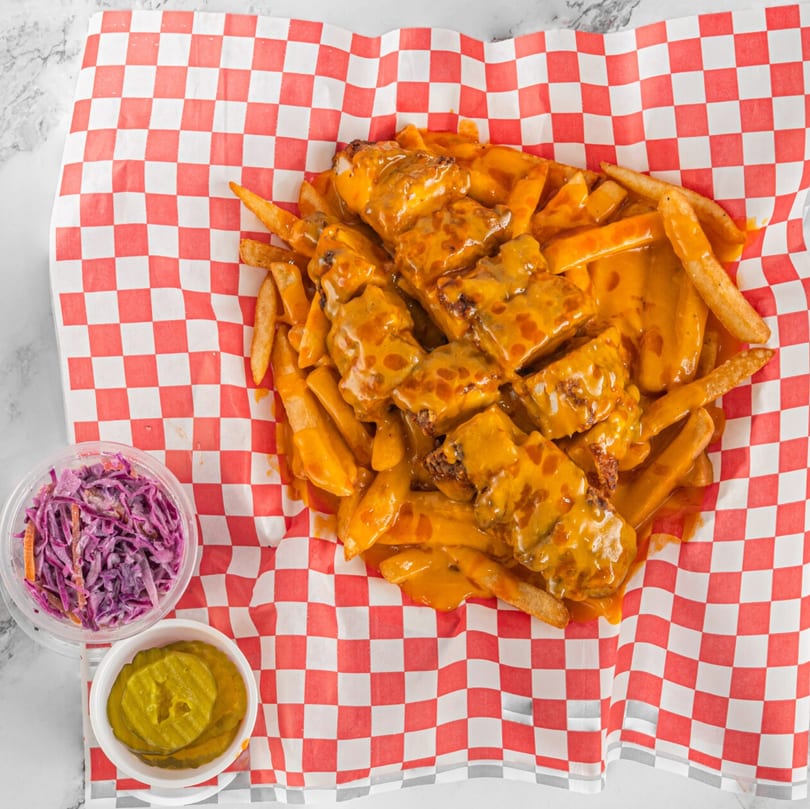 Hot Chicken and Breakfast's cheesy fries with chicken, coleslaw, and pickles on checkered paper.